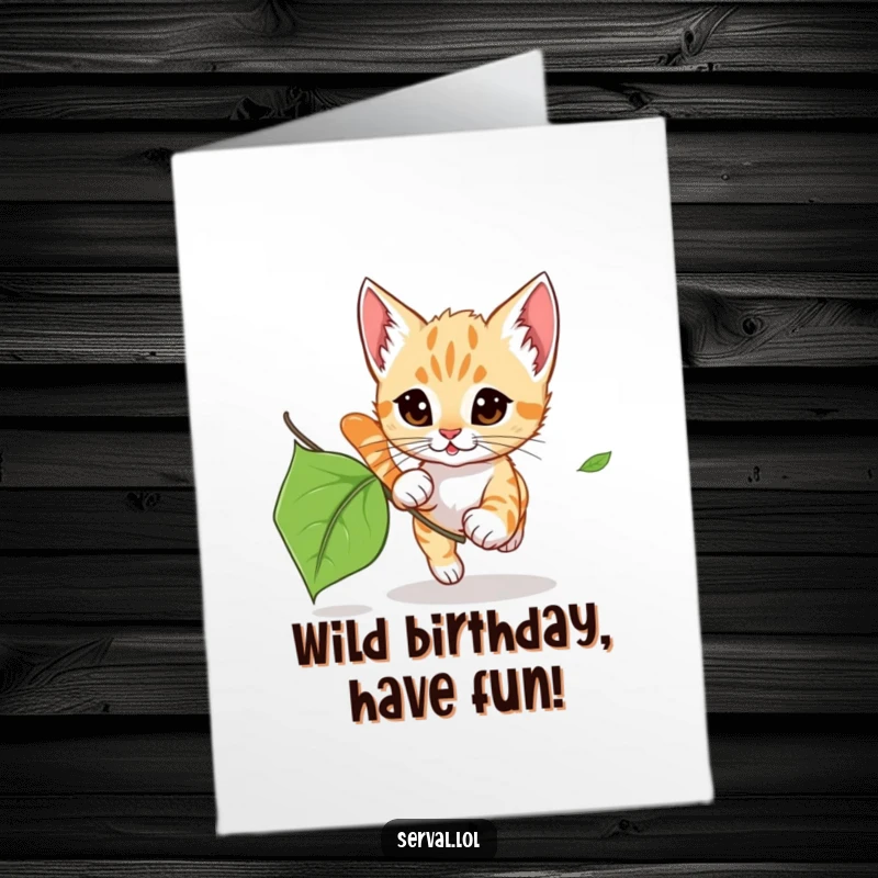 Adorable free printable birthday card showing a serval kitten playfully pouncing after a fluttering autumn leaf.