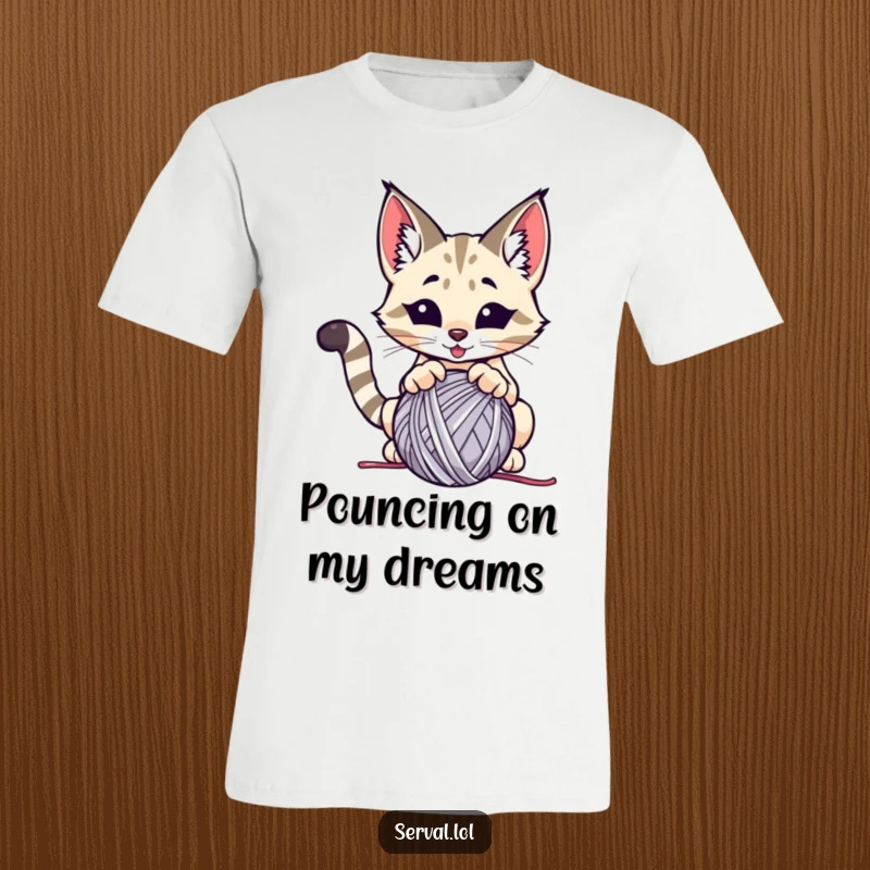 Funny serval t-shirt, a wild cat comically pouncing on a ball of yarn, showcasing energetic playfulness.